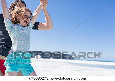 Stock Image - "Mother and daughter jumping in sea, Hot Water Beach, Bay of Islands, New Zealand". Fotosearch