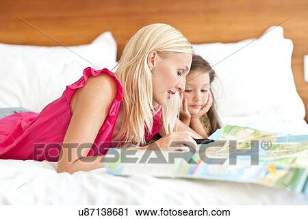 "Mother and daughter lying on bed, looking at map" View Large Photo Image Stock Image - "Mother and daughter lying on bed, looking at map". Fotosearch