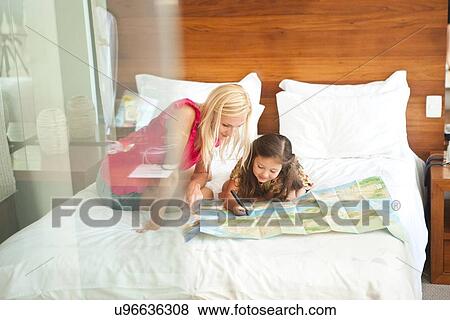 "Mother and daughter lying on bed, looking at map" View Large Photo Image Stock Photo - "Mother and daughter lying on bed, looking at map". Fotosearch