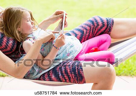 "Mother and daughter on hammock, using digital tablet" View Large Photo Image Picture - "Mother and daughter on hammock, using digital tablet". Fotosearch