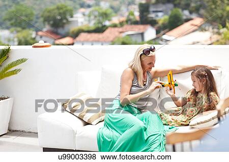 "Mother and daughter sitting outdoors, playing with top plane" View Large Photo Image Stock Photo - "Mother and daughter sitting outdoors, playing with top plane". Fotosearch