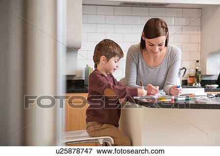 Stock Photo - Mother and son drawing together in kitchen. Fotosearch
