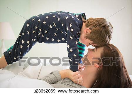 Stock Photo - Mother and son playing together in bed. Fotosearch