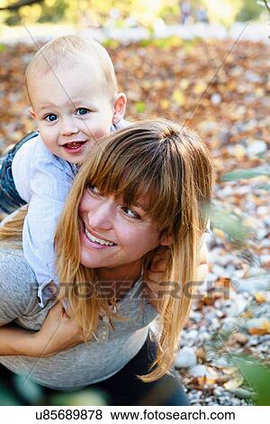 "Mother carrying son on back, outdoors" View Large Photo Image Stock Photo - "Mother carrying son on back, outdoors". Fotosearch