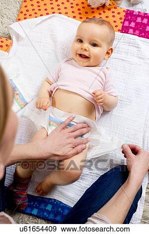 Mother changing nappy of baby girl View Large Photo Image Stock Photo - Mother changing nappy of baby girl. Fotosearch