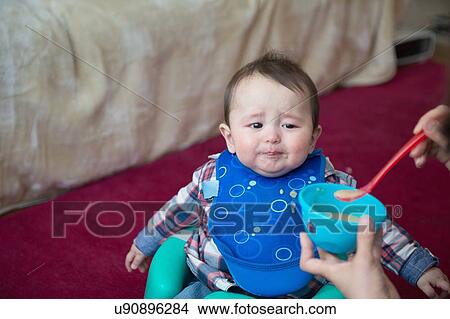 Picture - Mother feeding baby boy with spoon. Fotosearch