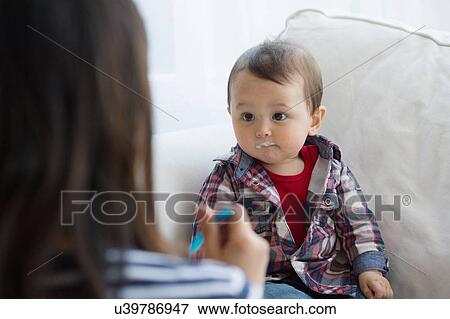 Mother feeding baby boy with spoon View Large Photo Image Stock Photo - Mother feeding baby boy with spoon. Fotosearch