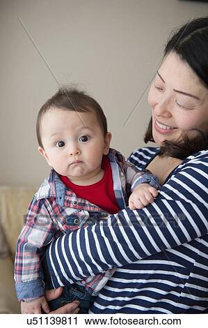 Stock Image - Mother holding baby boy in her arms. Fotosearch