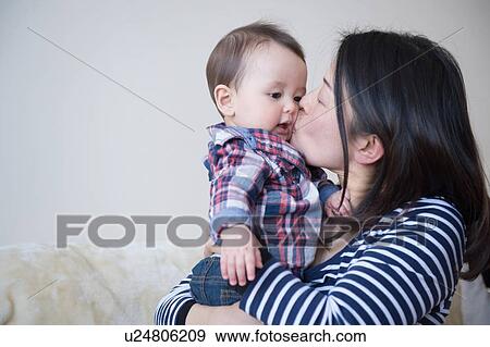 Mother kissing baby boy on cheek View Large Photo Image Stock Photo - Mother kissing baby boy on cheek. Fotosearch