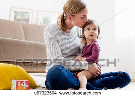 Picture - Mother kissing baby boy on head. Fotosearch