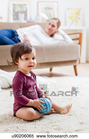 Mother lying on sofa watching baby boy play on floor View Large Photo Image Stock Photography - Mother lying on sofa watching baby boy play on floor. Fotosearch
