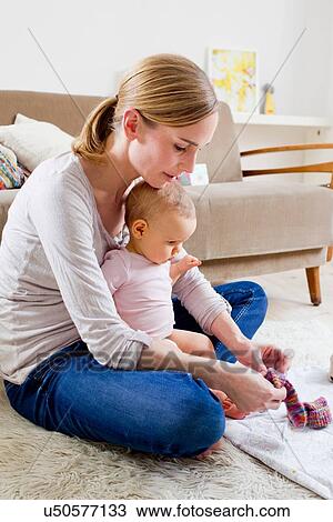 Mother putting socks on baby girl View Large Photo Image Stock Image - Mother putting socks on baby girl. Fotosearch