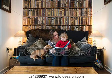 Stock Photo - Mother reading book to son on sofa. Fotosearch