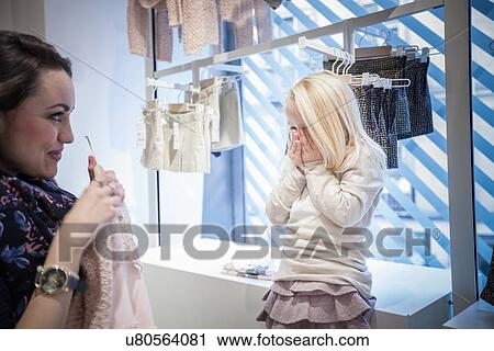Mother showing dress to young daughter in childrens clothes shop View Large Photo Image Stock Image - Mother showing dress to young daughter in childrens clothes shop. Fotosearch