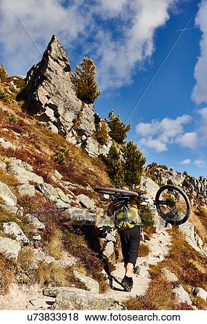 Stock Photo - "Mountain biker carrying bike, Valais, Switzerland". Fotosearch