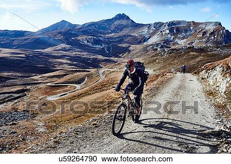Stock Image - "Mountain biker on dirt track, Valais, Switzerland". Fotosearch