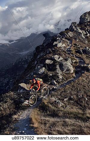 Stock Image - "Mountain biker on dirt track, Valais, Switzerland". Fotosearch