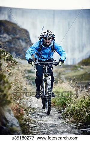 Stock Photo - "Mountain biker on dirt track, Valais, Switzerland". Fotosearch