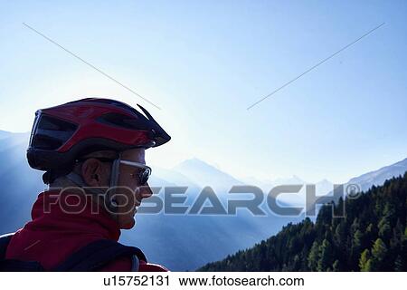 Stock Image - "Mountain biker wearing helmet in mountains, Valais, Switzerland". Fotosearch