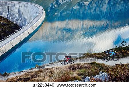 "Mountain bikers by reservoir, Valais, Switzerland" View Large Photo Image Stock Image - "Mountain bikers by reservoir, Valais, Switzerland". Fotosearch