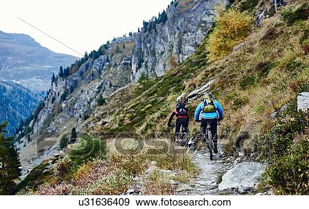Stock Photo - "Mountain bikers on dirt track, Valais, Switzerland". Fotosearch