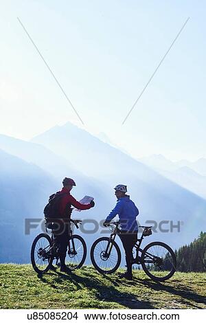 Picture - "Mountain bikers with map, Valais, Switzerland". Fotosearch