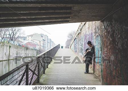 "Musician playing guitar by canal wall, Milan, Italy" View Large Photo Image Stock Photograph - "Musician playing guitar by canal wall, Milan, Italy". Fotosearch