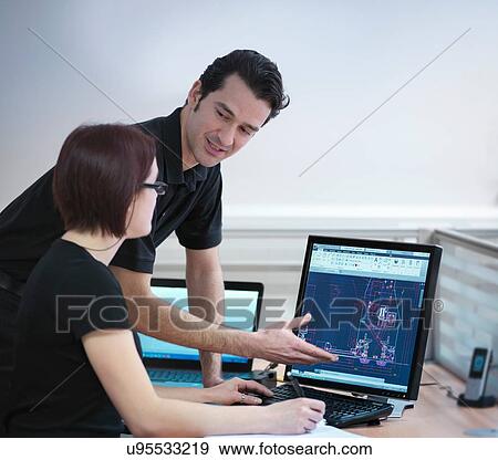 Stock Photo - Office workers looking at CAD drawings in carbon fibre factory. Fotosearch