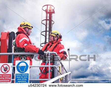 Offshore windfarm workers in discussion on jetty at sea View Large Photo Image Picture - Offshore windfarm workers in discussion on jetty at sea. Fotosearch