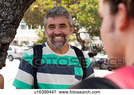 Stock Photo - "Over shoulder portrait of father and son on sidewalk, Copacabana, Rio De Janeiro, Brazil". Fotosearch