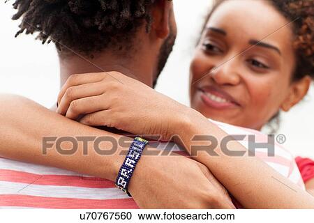 Stock Image - "Over shoulder view of couple hugging, Ipanema beach, Rio De Janeiro, Brazil". Fotosearch