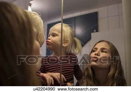 Over the shoulder view of female toddler and mother puckering lips in bathroom mirror View Large Photo Image Stock Image - Over the shoulder view of female toddler and mother puckering lips in bathroom mirror. Fotosearch