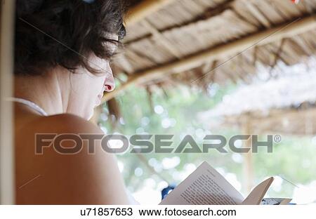 "Over the shoulder view of woman reading outside beach hut, Kradan, Thailand" View Large Photo Image Stock Image - "Over the shoulder view of woman reading outside beach hut, Kradan, Thailand". Fotosearch