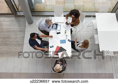 Overhead view of business team having meeting at conference table View Large Photo Image Stock Photo - Overhead view of business team having meeting at conference table. Fotosearch