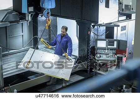 Stock Photograph - Overview of worker with large CNC machine in plastics factory. Fotosearch