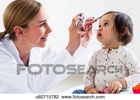 Stock Image - Paediatrician checking baby boy's eyes. Fotosearch