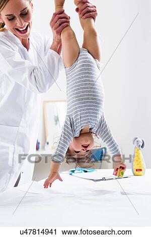 Paediatrician holding baby boy upside-down View Large Photo Image Stock Image - Paediatrician holding baby boy upside-down. Fotosearch