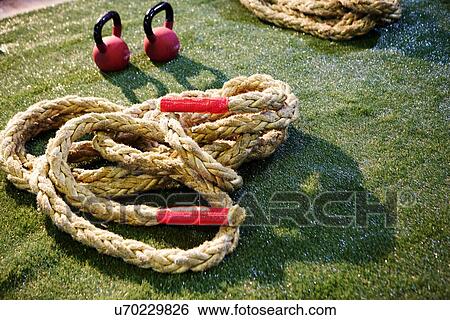 Stock Photograph - Pair of kettlebells and gym ropes on lawn. Fotosearch