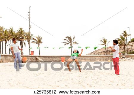 Stock Image - "People limbo dancing on beach, Rio de Janeiro, Brazil". Fotosearch