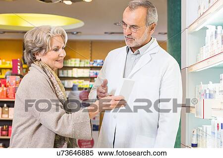 Stock Photography - Pharmacist advising senior woman on medicine in pharmacy. Fotosearch