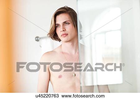 Stock Image - Portrait of bare chested young man in hotel bathroom. Fotosearch