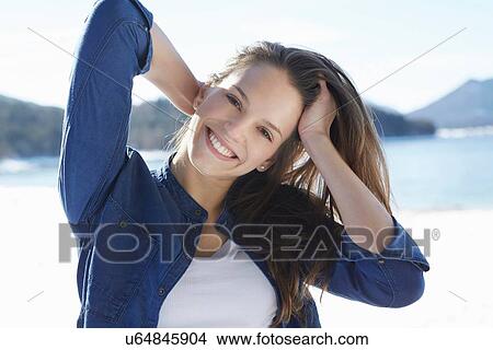 "Portrait of beautiful young woman with hand in hair at snow covered lakeside, German Alps, Germany" View Large Photo Image Picture - "Portrait of beautiful young woman with hand in hair at snow covered lakeside, German Alps, Germany". Fotosearch