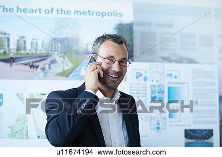 Picture - Portrait of business man chatting on smartphone in office. Fotosearch