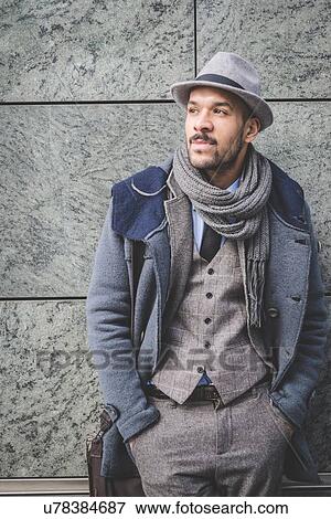 Stock Photo - Portrait of businessman leaning against wall with hands in pockets. Fotosearch