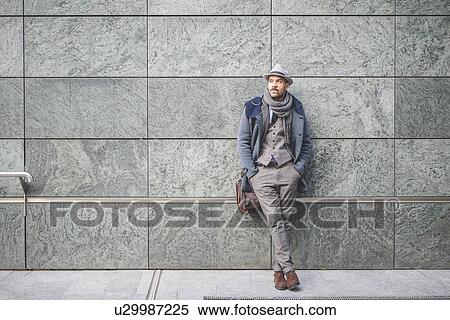 Stock Photography - Portrait of businessman leaning against wall. Fotosearch
