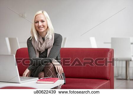 Stock Photo - Portrait of businesswoman using laptop on office sofa. Fotosearch