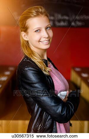 Stock Photography - Portrait of confident young woman with arms folded in cafe. Fotosearch