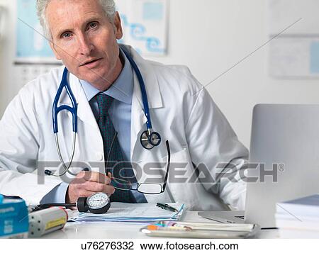 Stock Image - Portrait of doctor consulting a patient in office. Fotosearch