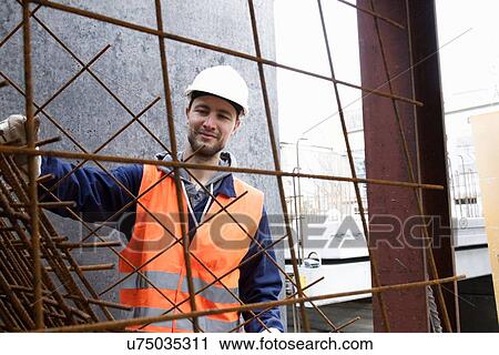 Stock Image - Portrait of factory worker selecting steel mesh at concrete reinforcement factory. Fotosearch