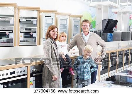 Stock Photo - Portrait of family with two children browsing hobs in electronics store. Fotosearch